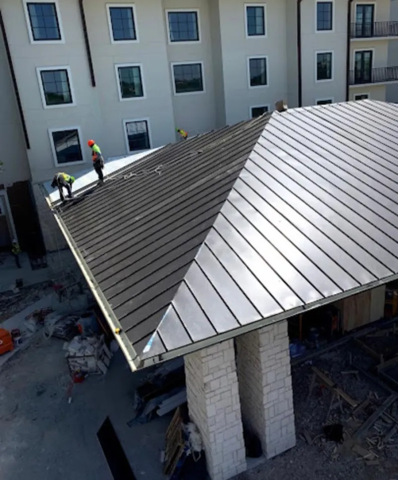 Crew installing standing seam metal roof panels on a commercial project in Williston